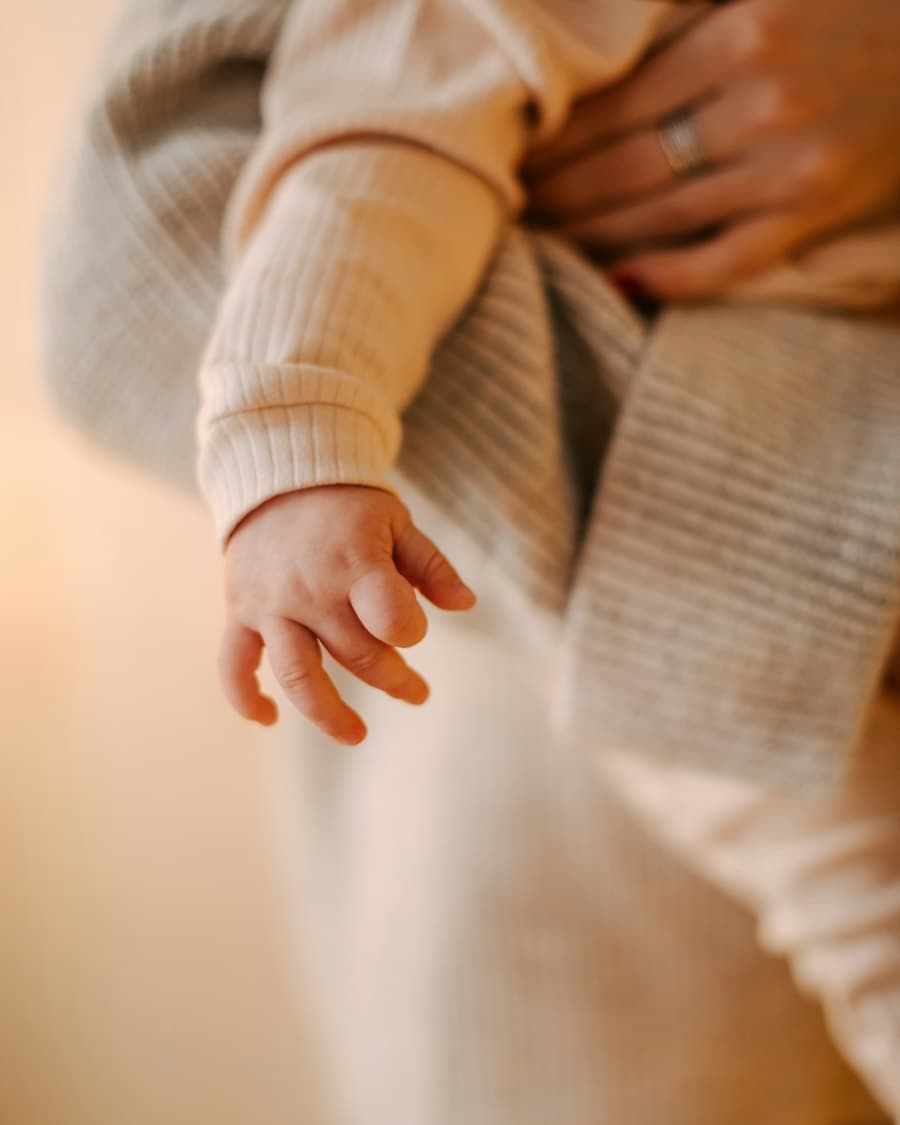 A baby's hand resting on a mother's knitted sweater